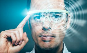 Man wears a virtual reality headset that gives him the opportunity to experience the world in a new way. He operates the glasses by toucing them on the side. Content shows up in front of the man.